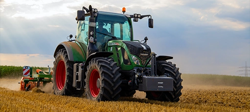 A large green tractor plows a field.